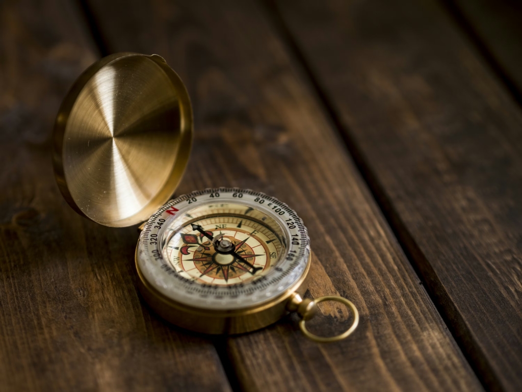 A gold compass on a dark wooden table
