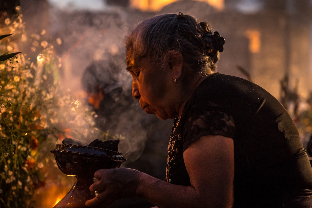 A woman blows smoke from burning copal as a blessing.