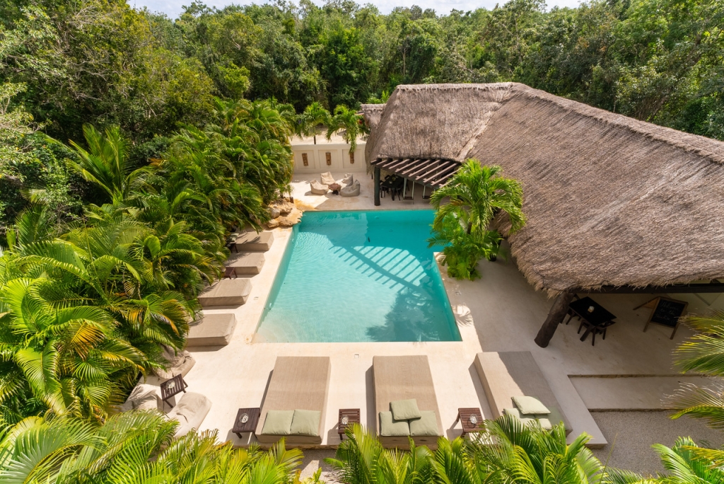 Aeiral shot of an ibogaine clinic in Mexico within a jungle, thatch building, and a pool.