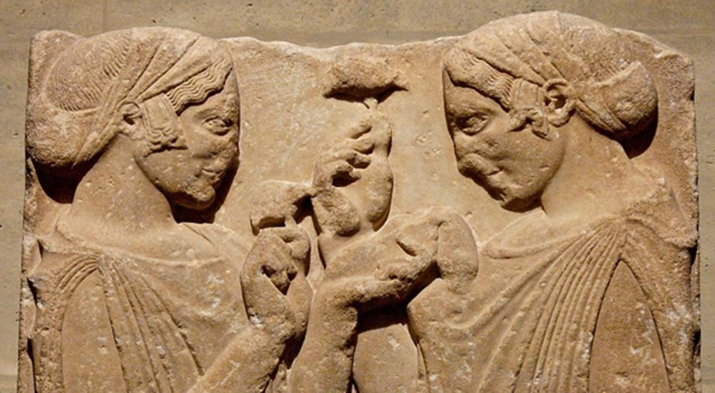 Ancient stone carving of two women holding psilocybin mushrooms