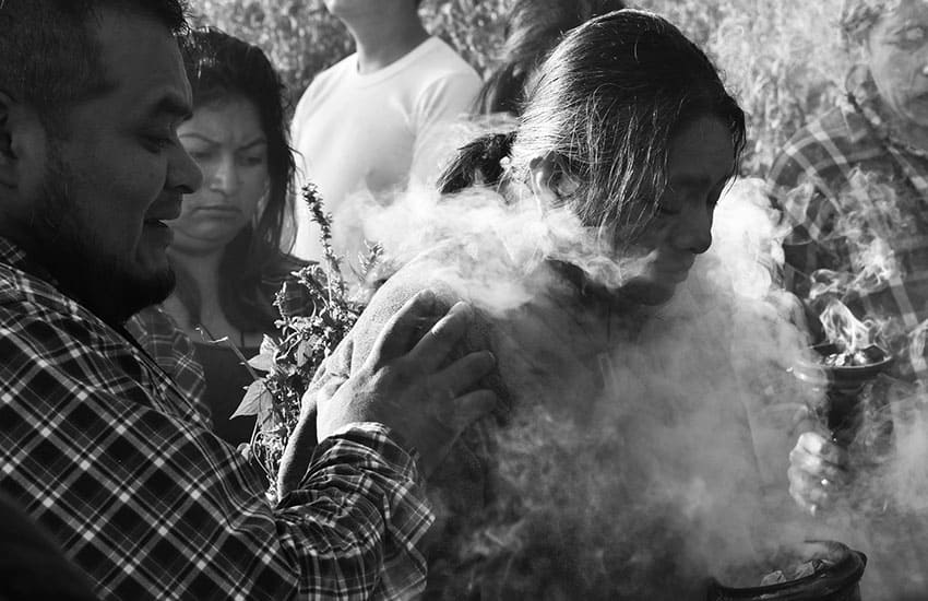 Black and white photo of woman being smudged and cleansed by a man before a mushroom ceremony.