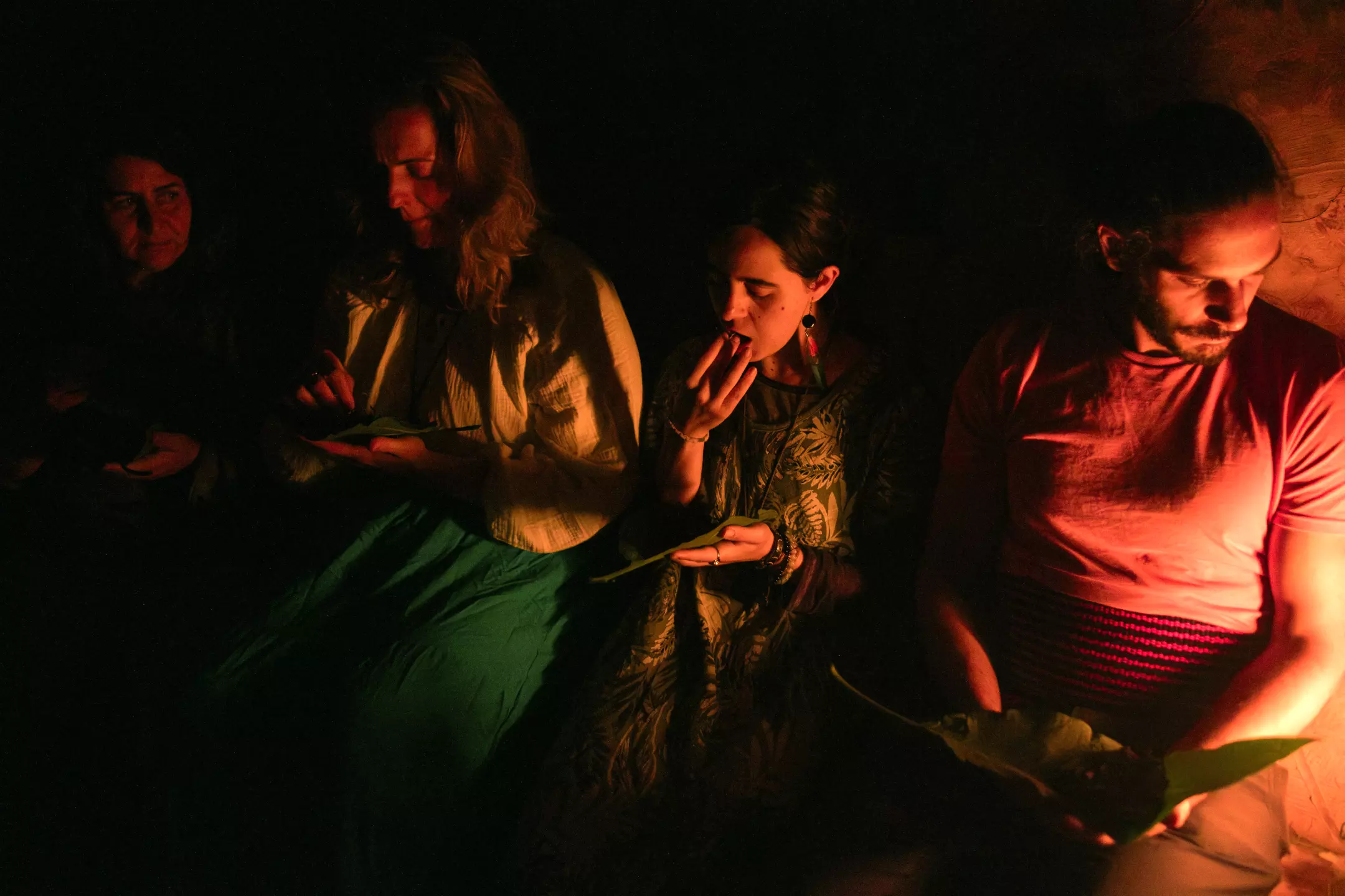 four people in a psilocybin mushroom ceremony, with a woman ingesting the mushrooms.